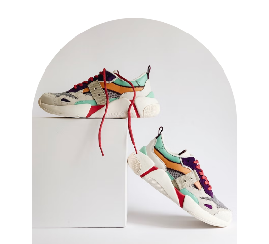 Färgglada sneakers med röda skosnören, placerade på och bredvid en vit piedestal