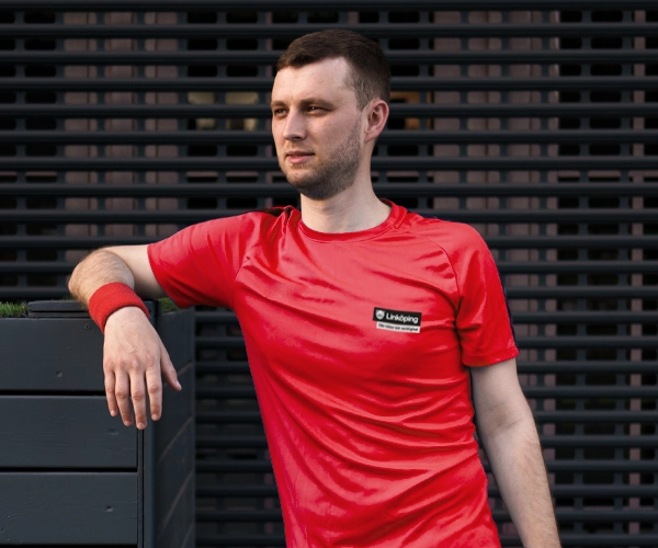Man klädd i röd Dri-Fit tröja med Linköpings logotyp på vänster bröst